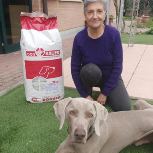 Signora bionda con un cane da Pastore Tedesco, un meticcio e il sacco delle crocchette Low Grain Dogbauer