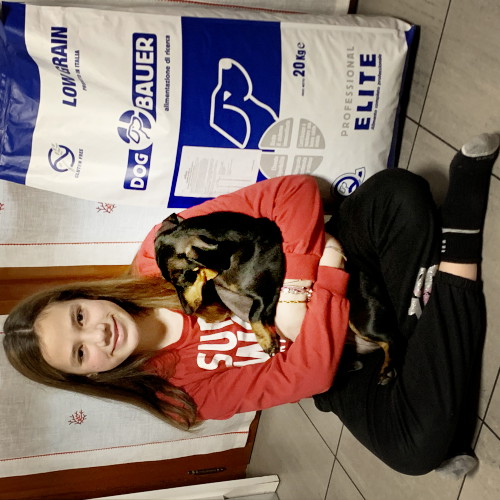 Uomo seduto sul divano con il suo cane Pointer e davanti il sacco di crocchette Dogbauer