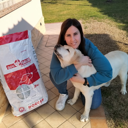 Ragazza che abbraccia il suo splendido Labrador , a fianco il sacco delle sue crocchette Dogbauer